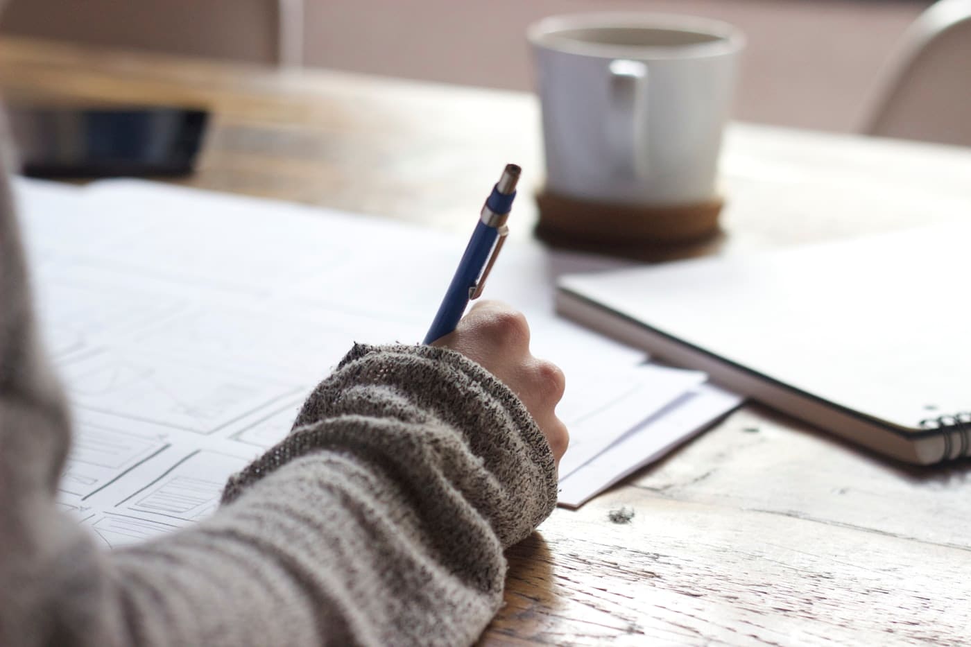 A student writing an application at a desk beside a notebook