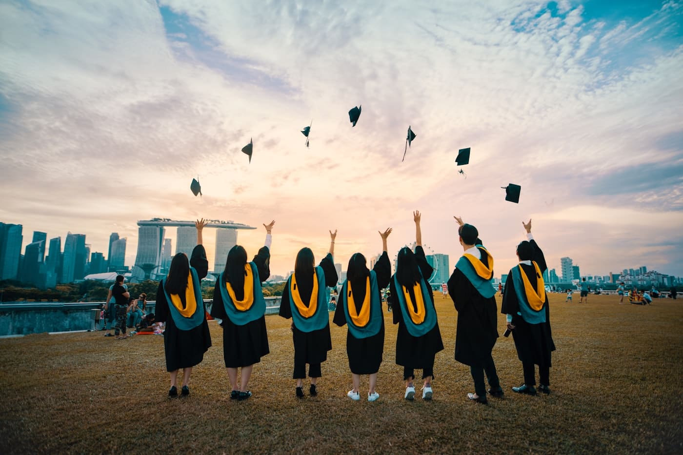 Graduates throwing their caps against a city skyline at sunset